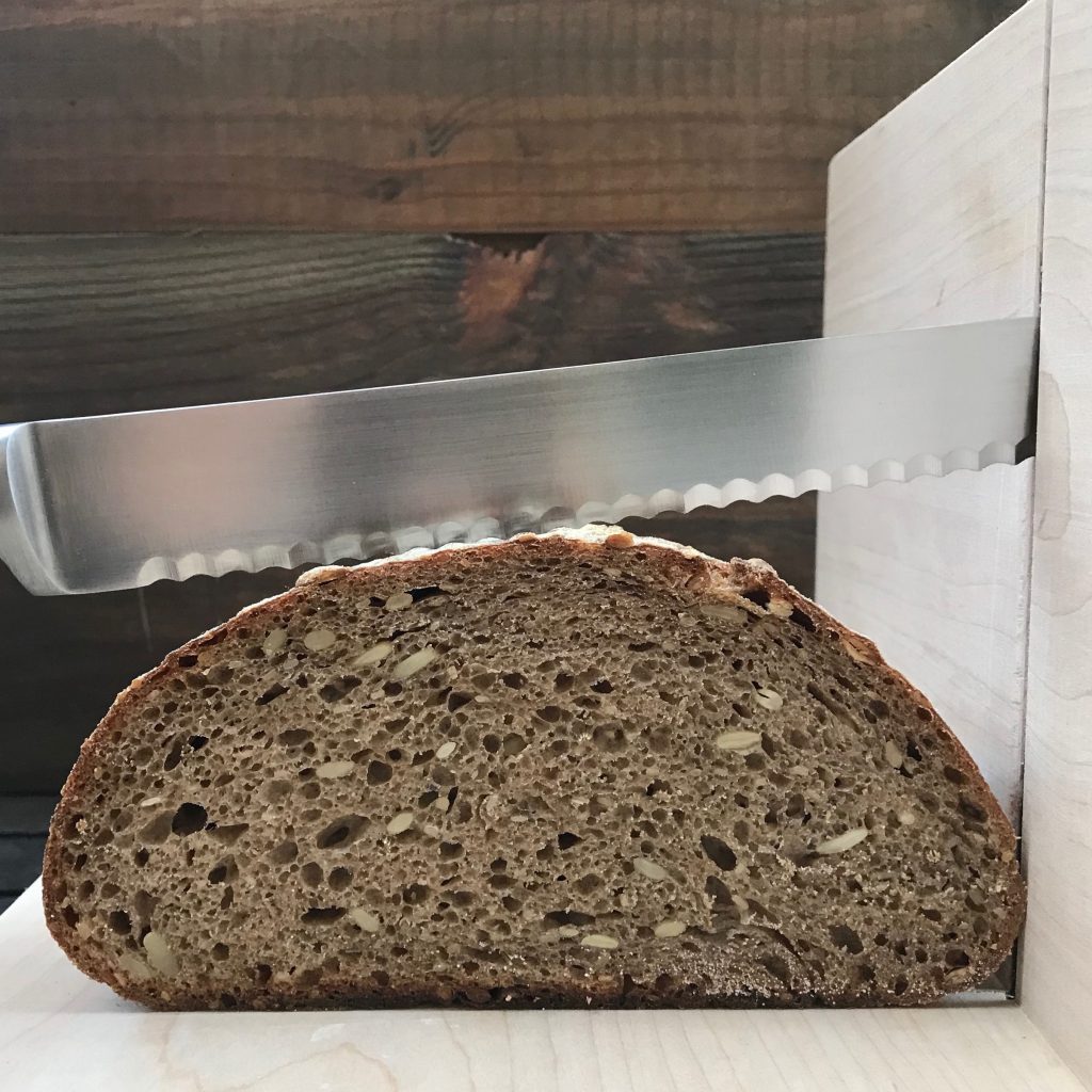 loaf of sourdough bread being sliced with a serrated knife