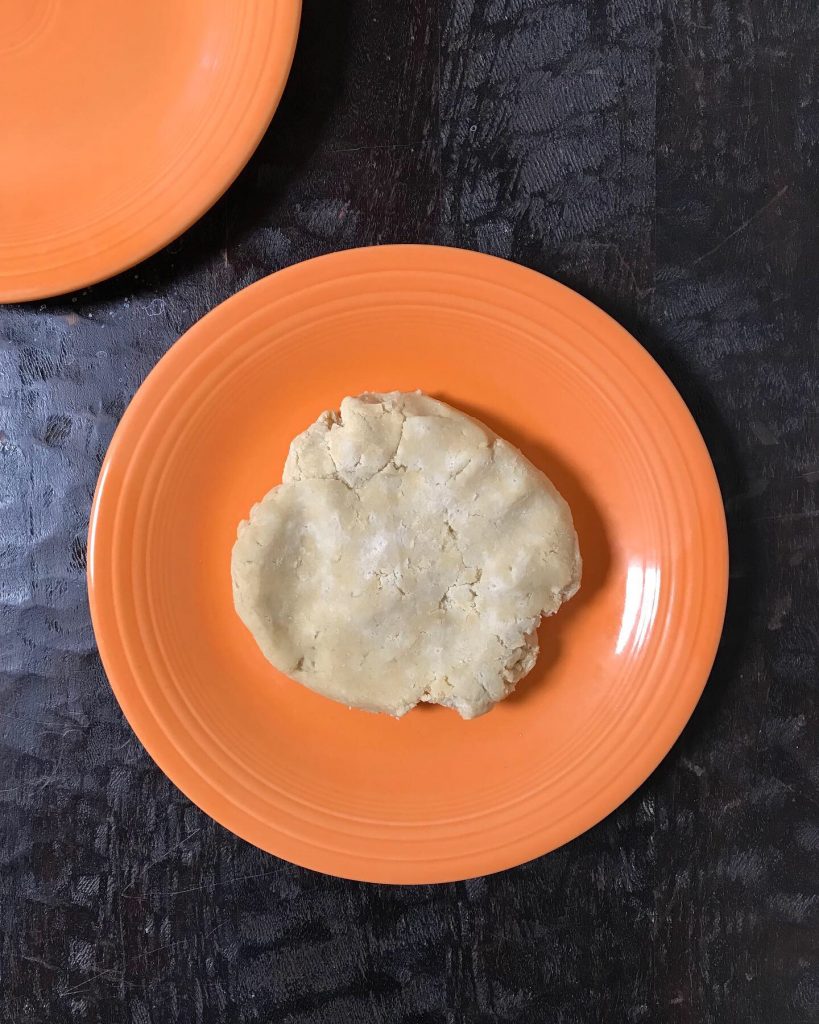 a disk of pastry dough rests in the center of an orange plate