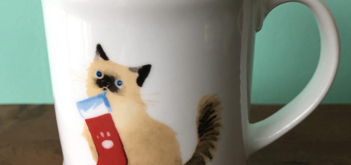 ceramic coffee mug with a cat holding a Christmas stocking in its teeth