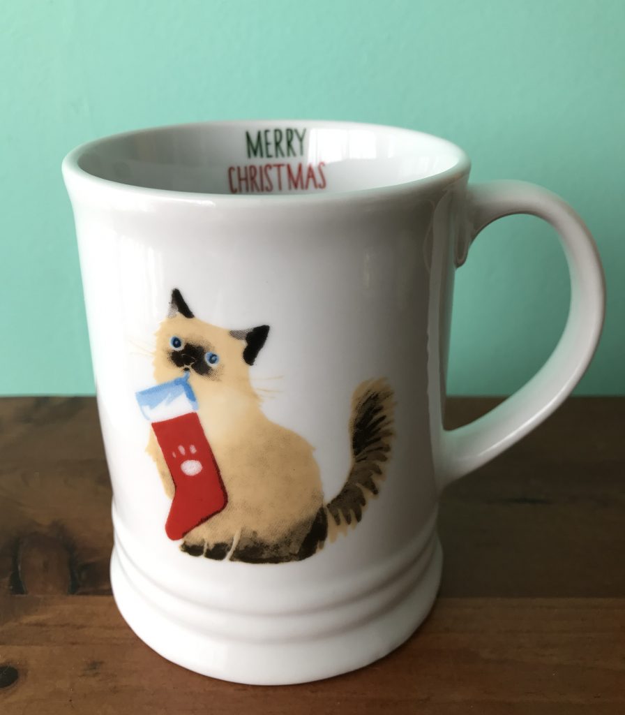 ceramic coffee mug with a cat holding a Christmas stocking in its teeth