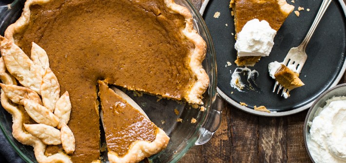 pumpkin pie in a pie dish with a slice cut and a slice on a plate