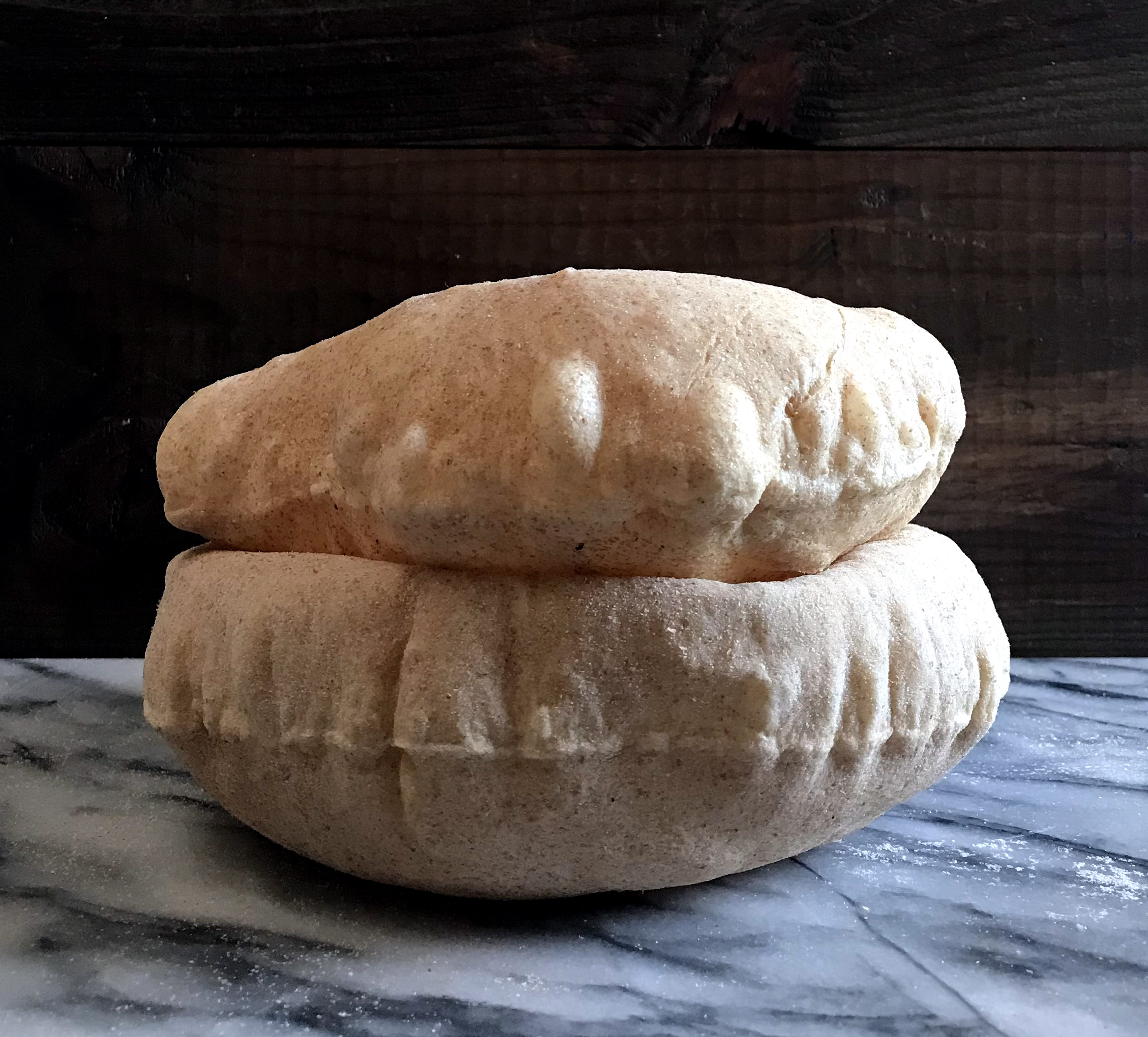 two freshly baked pitas filled with air, stacked one on the other