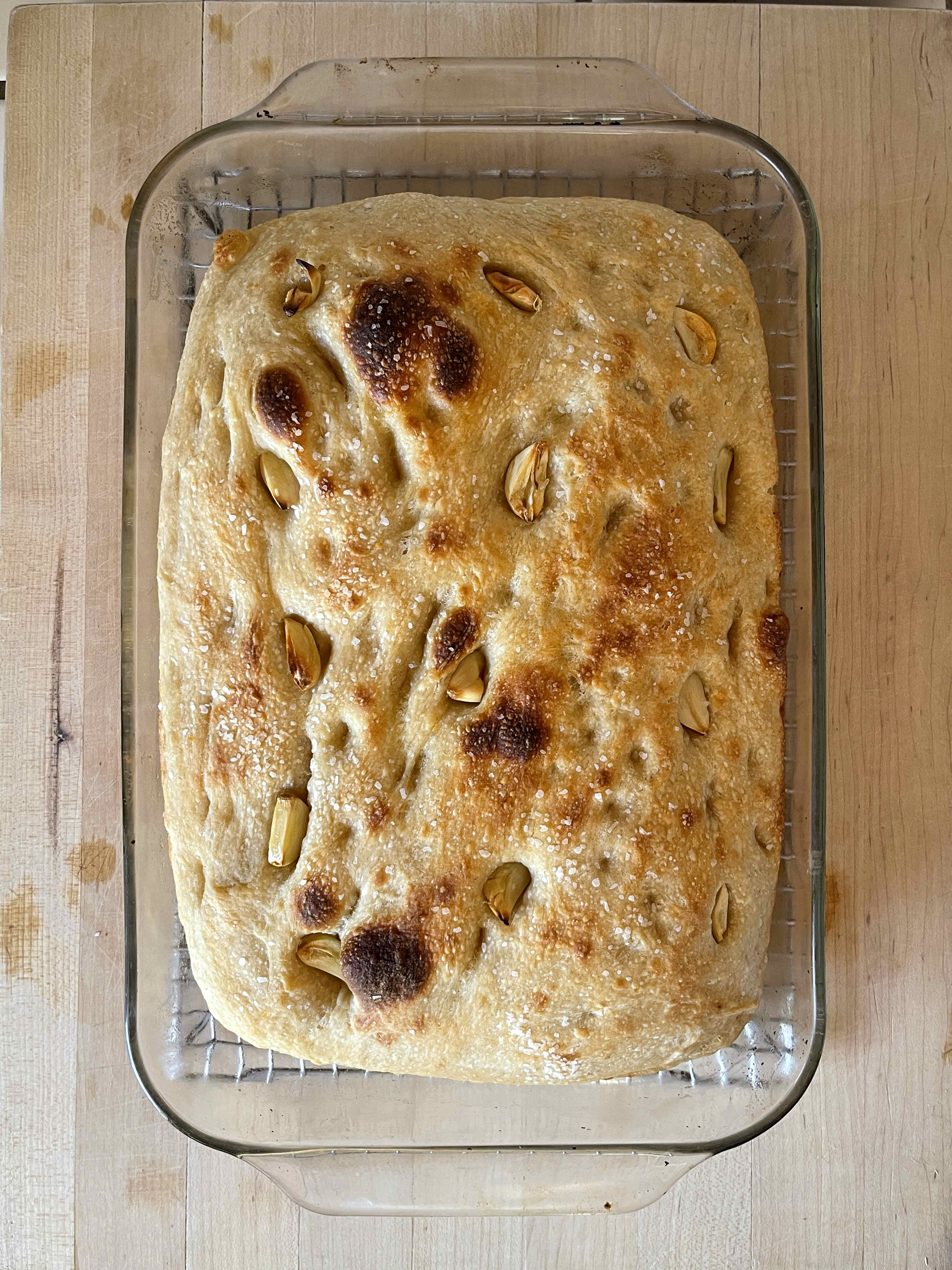 slab of sourdough–potato focaccia cooling in a rectangular glass baking dish set on a wire rack