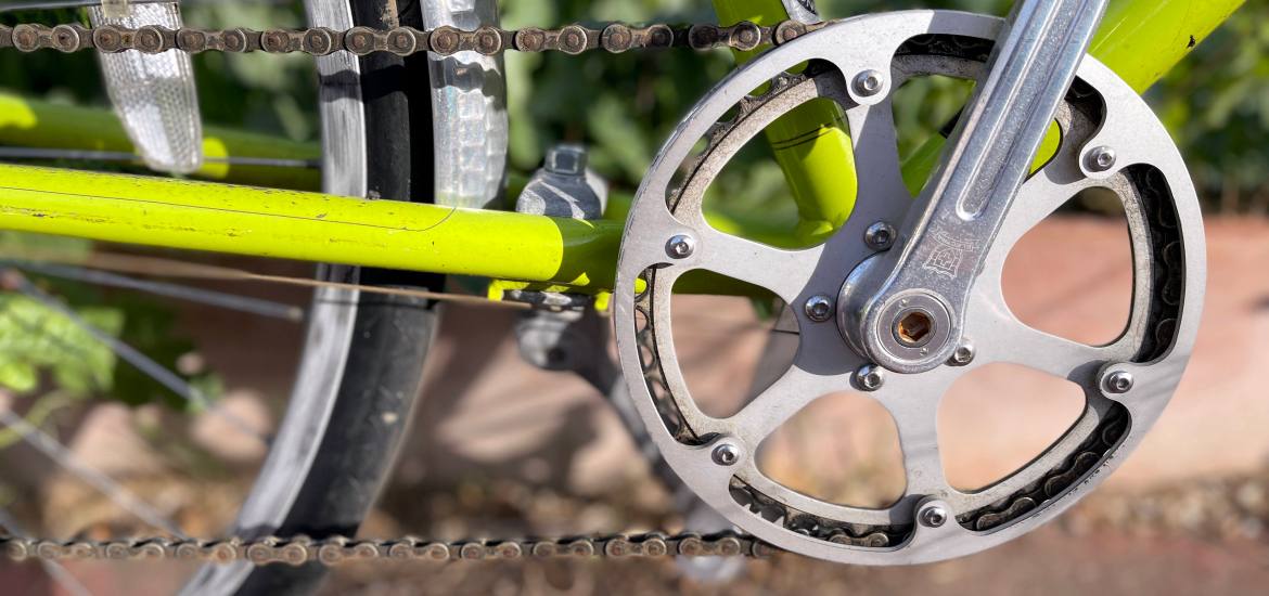 close up of a bike chain on a green bicycle