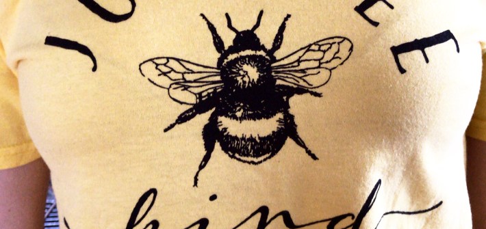 A yellow t-shirt with a bee in the center says "Just Bee Kind"