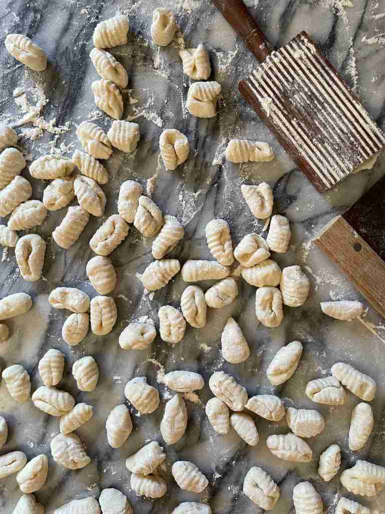 Gnocchi sitting on a gray and white marble background before cooking