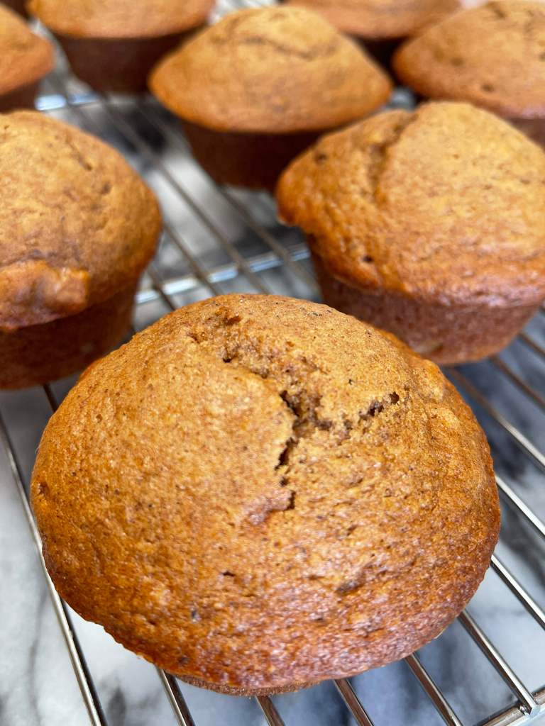 Baked pumpkin muffins with sourdough dicard cool on a cooling rack set on grey and white marble