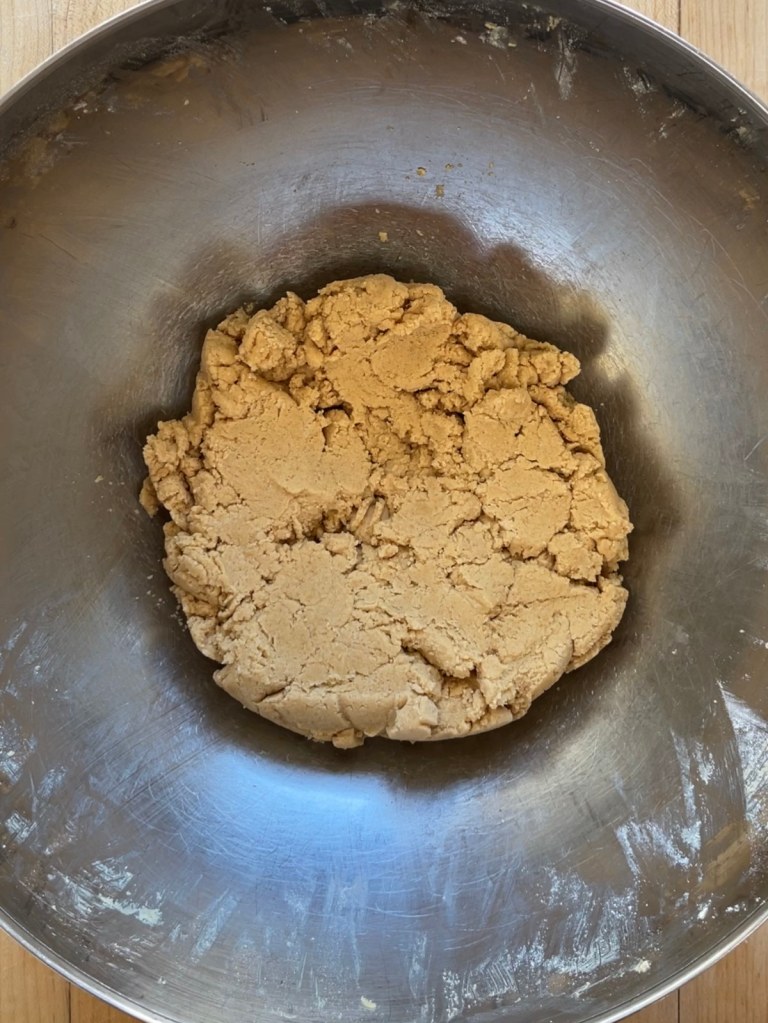 A stainless steel bowl of peanut butter cookie dough made with a sourdough discard flax egg