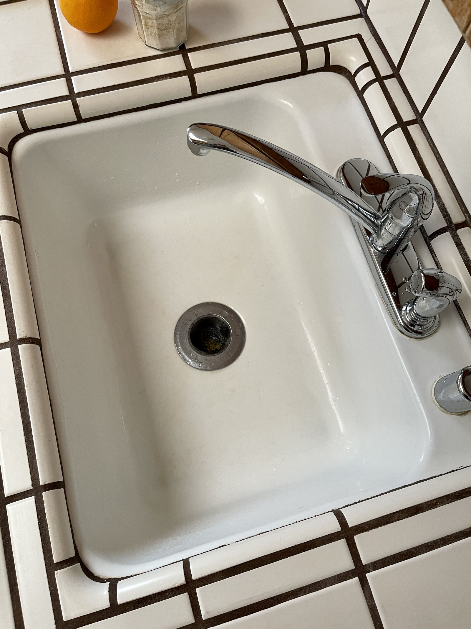 White porcelain kitchen sink after cleaning with homemade scouring powder containing dried citrus zest.