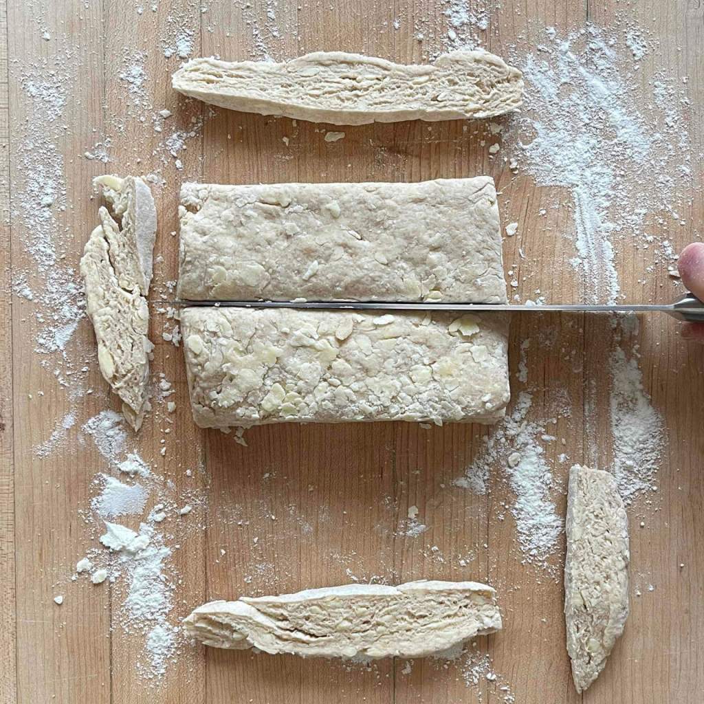 A knife cutting through sourdough biscuit dough to form shapes