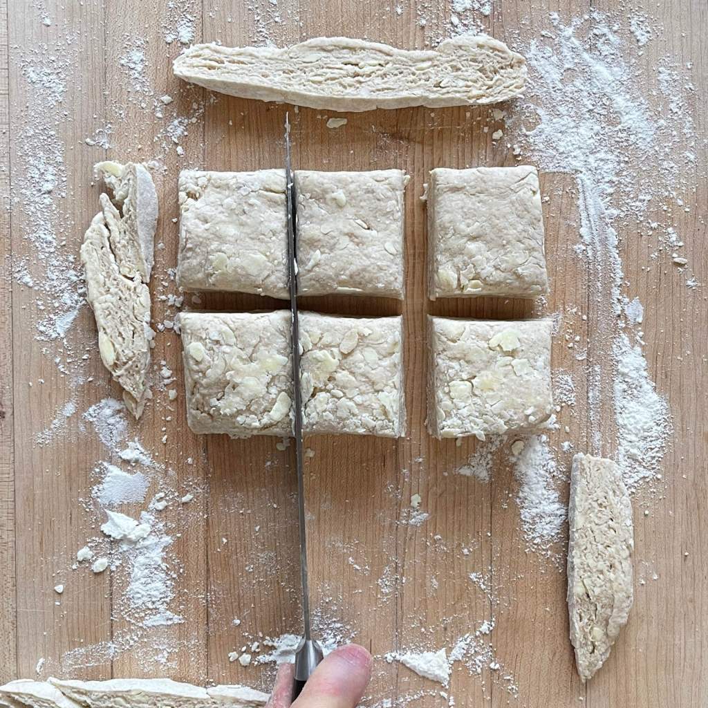 A knife cuts sourdough biscuit dough into squares before baking