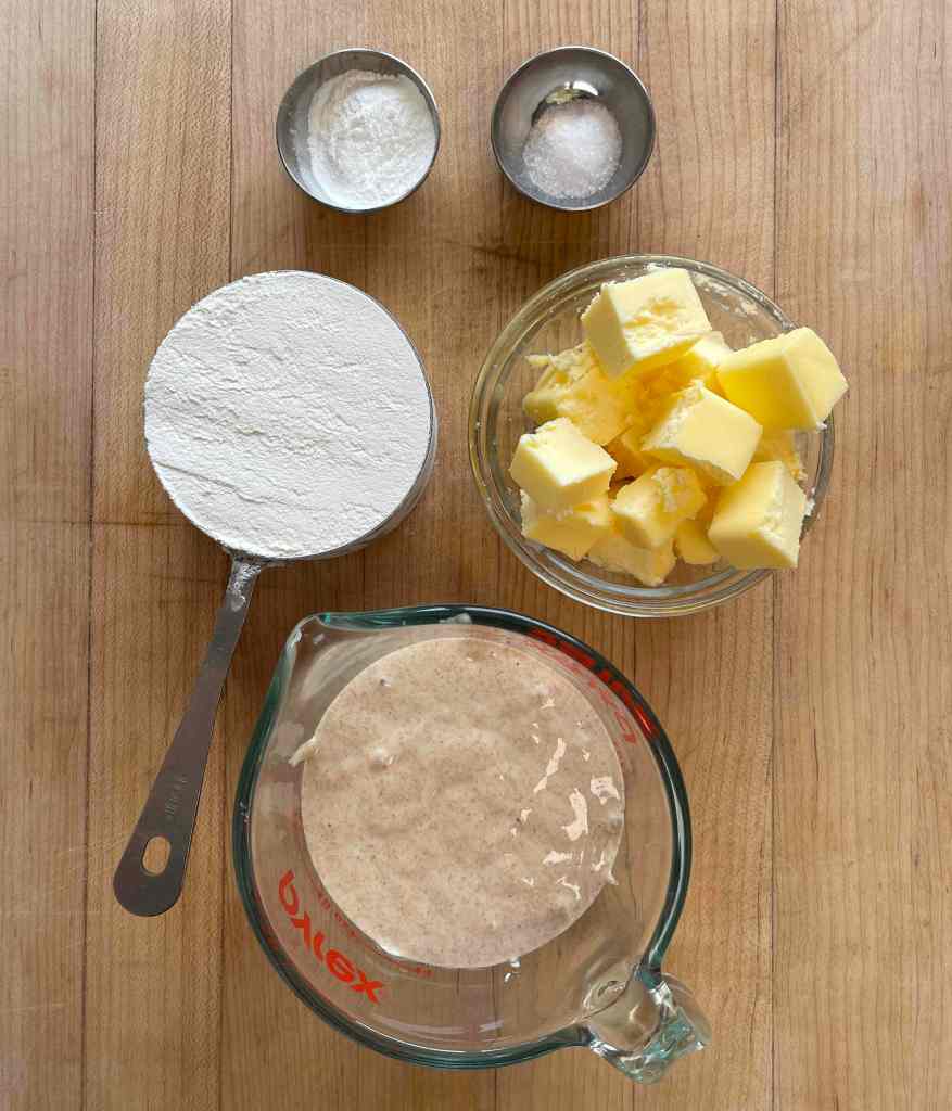 Sourdough discard biscuit ingredients sit on a light wooden background
