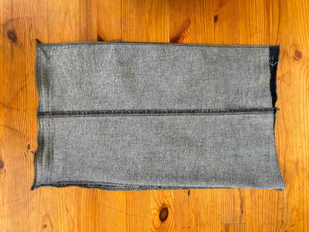 An inside-out denim garden cushion open on one end for stuffing sits on a wooden table