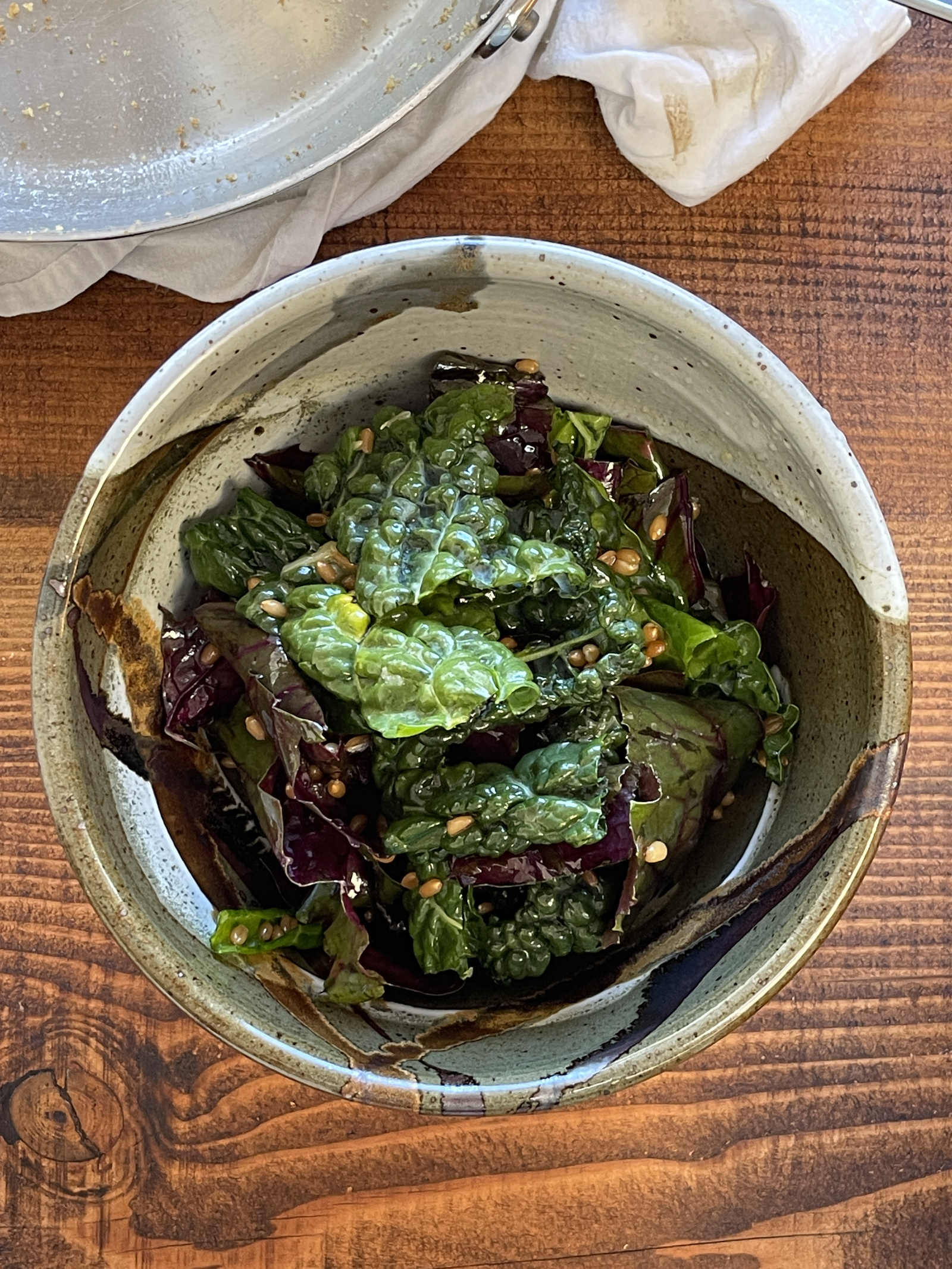 A ceramic bowl of kale, wheat berry and preserved lemon salad sits on a dark wooden table.