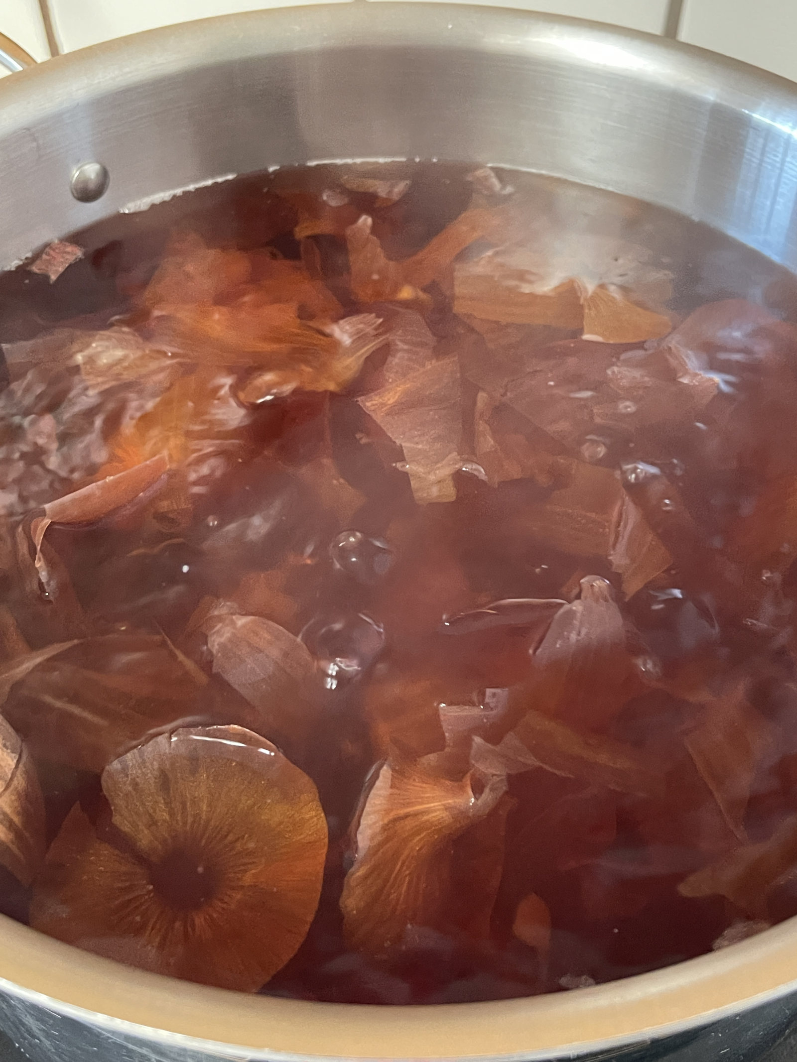 Simmering onion skins in water in a large stainless steel pot to make onion skin dye