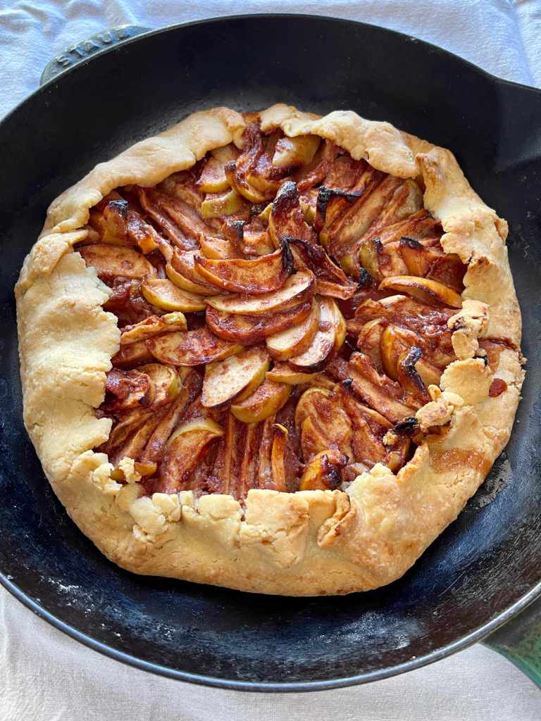 A baked apple galette made with semolina pastry cools in a cast-iron pan