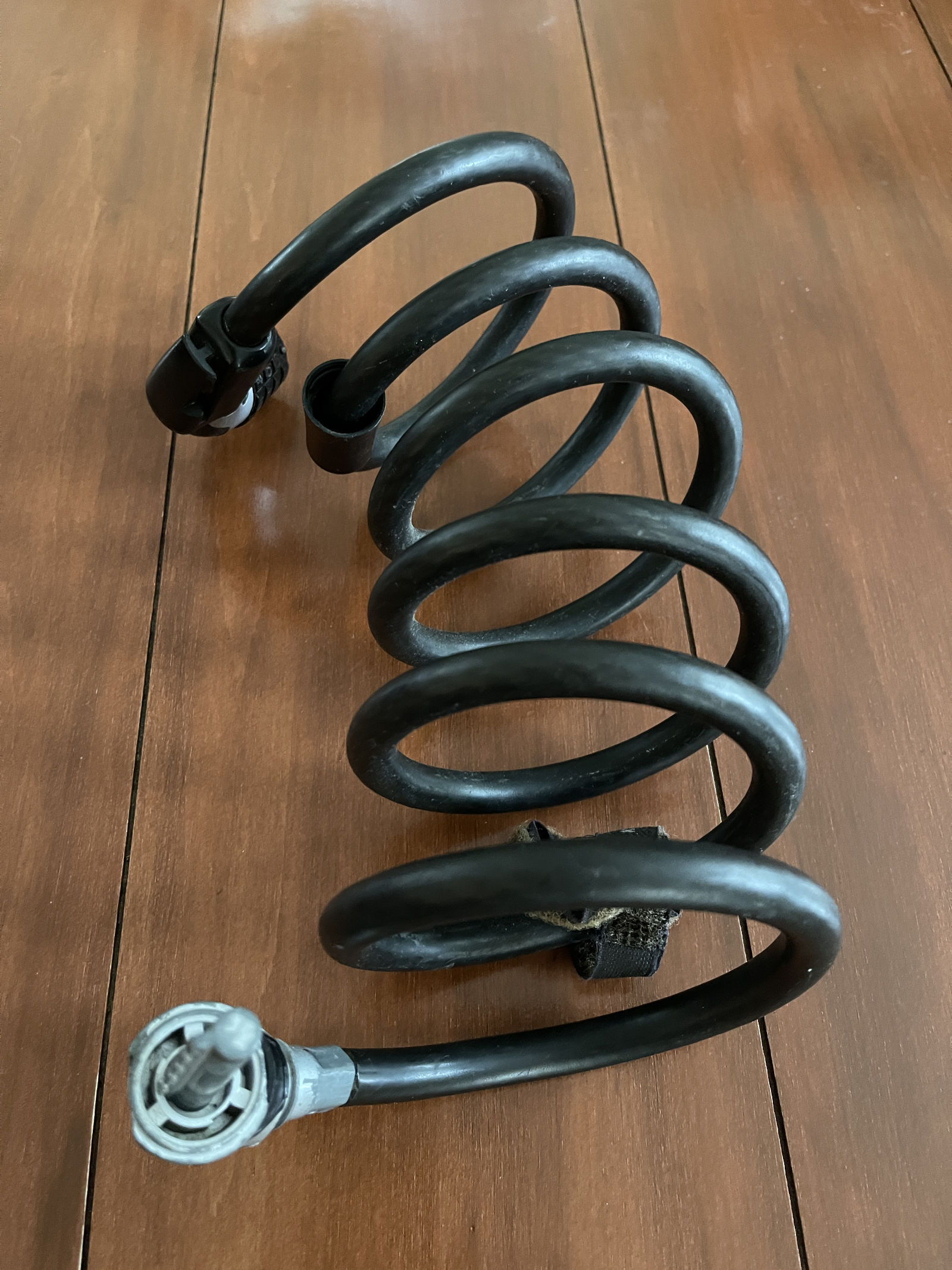 A heavy-duty black combination bike lock sits on a wooden backdrop