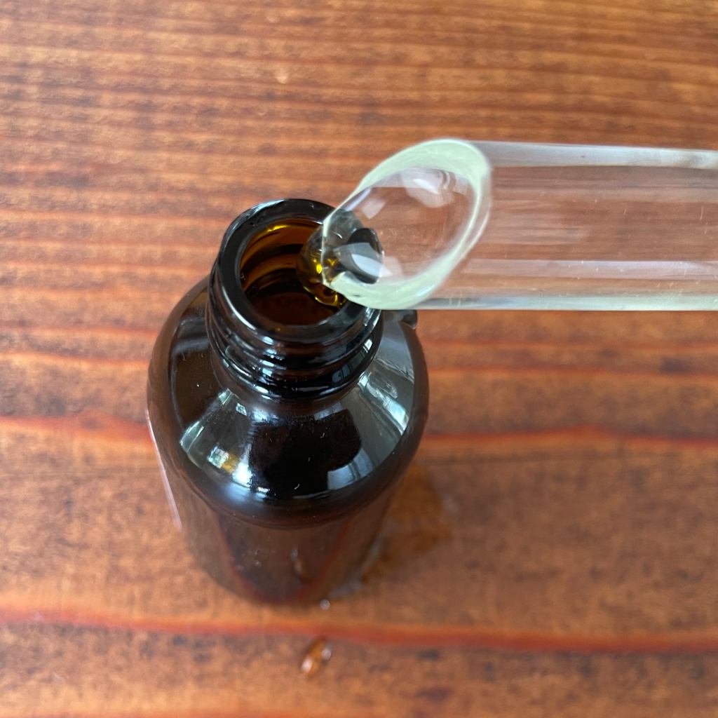 Filling a small brown bottle with homemade glasses cleaner