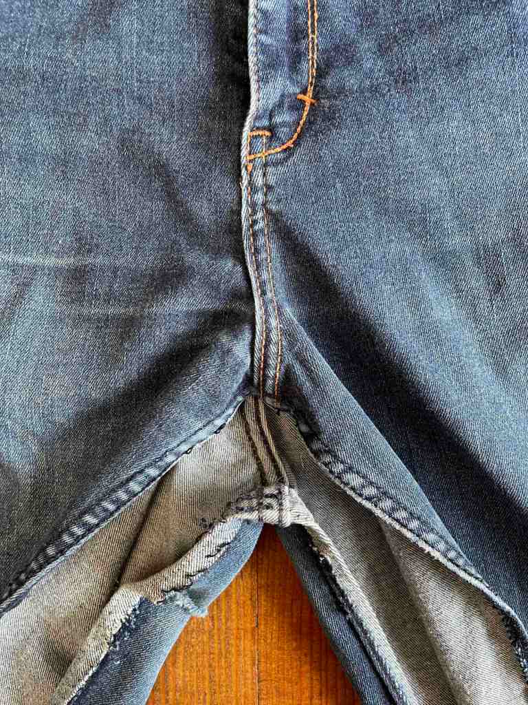 The inner seams of a pair of jeans ripped out to sew a shopping bag