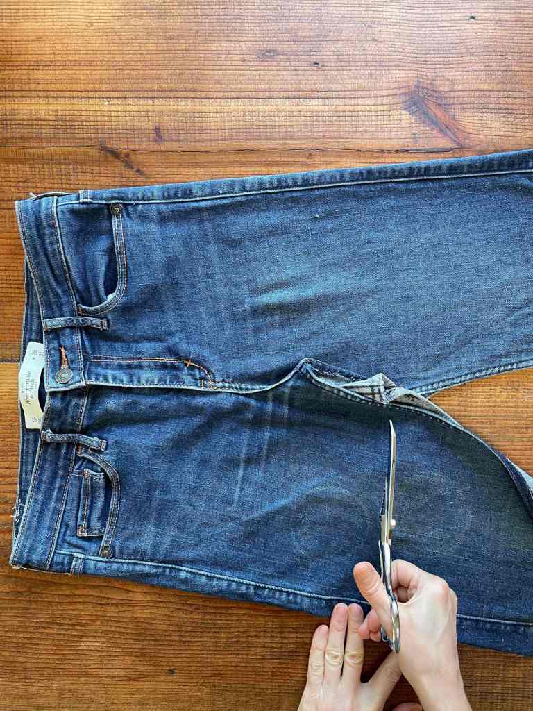 Scissors cut the legs off a pair of jeans that is being turned into a denim shopping bag