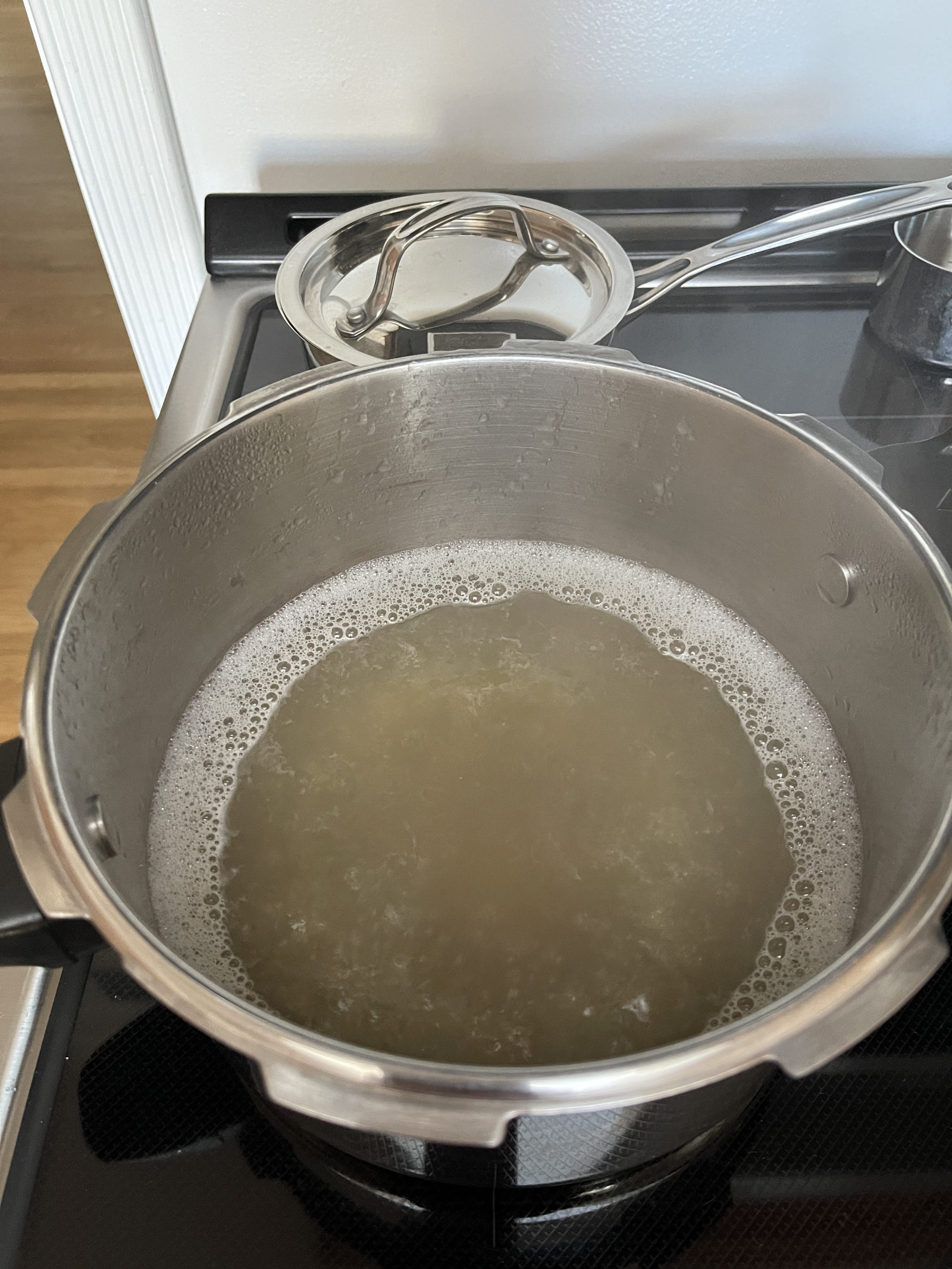 A pot of liquid leftover from cooking chickpeas simmers and foams on a stove