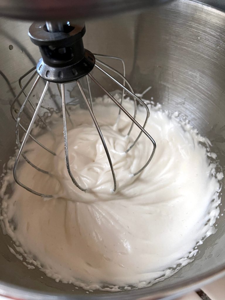 Aquafaba is being whipped into stiff peaks in a stand mixer