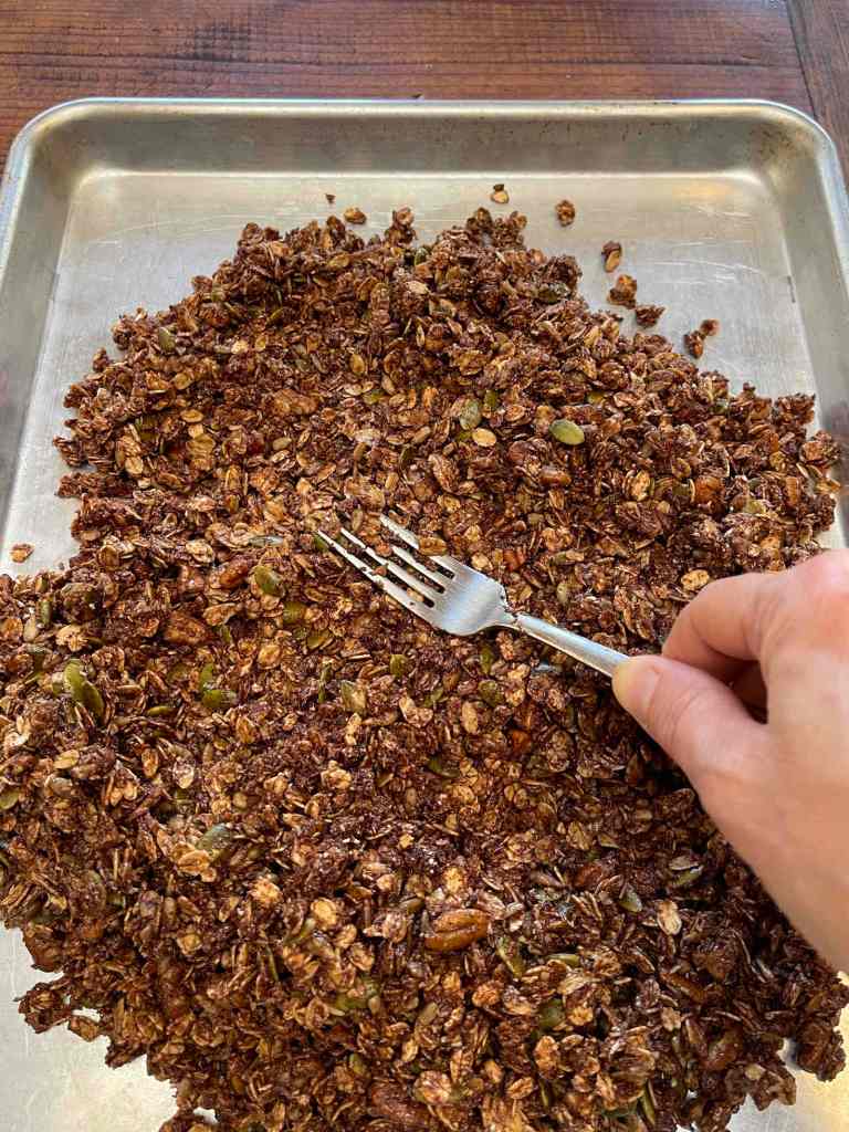 Spreading chocolate and nut granola mixture onto an ungreased cookie sheet