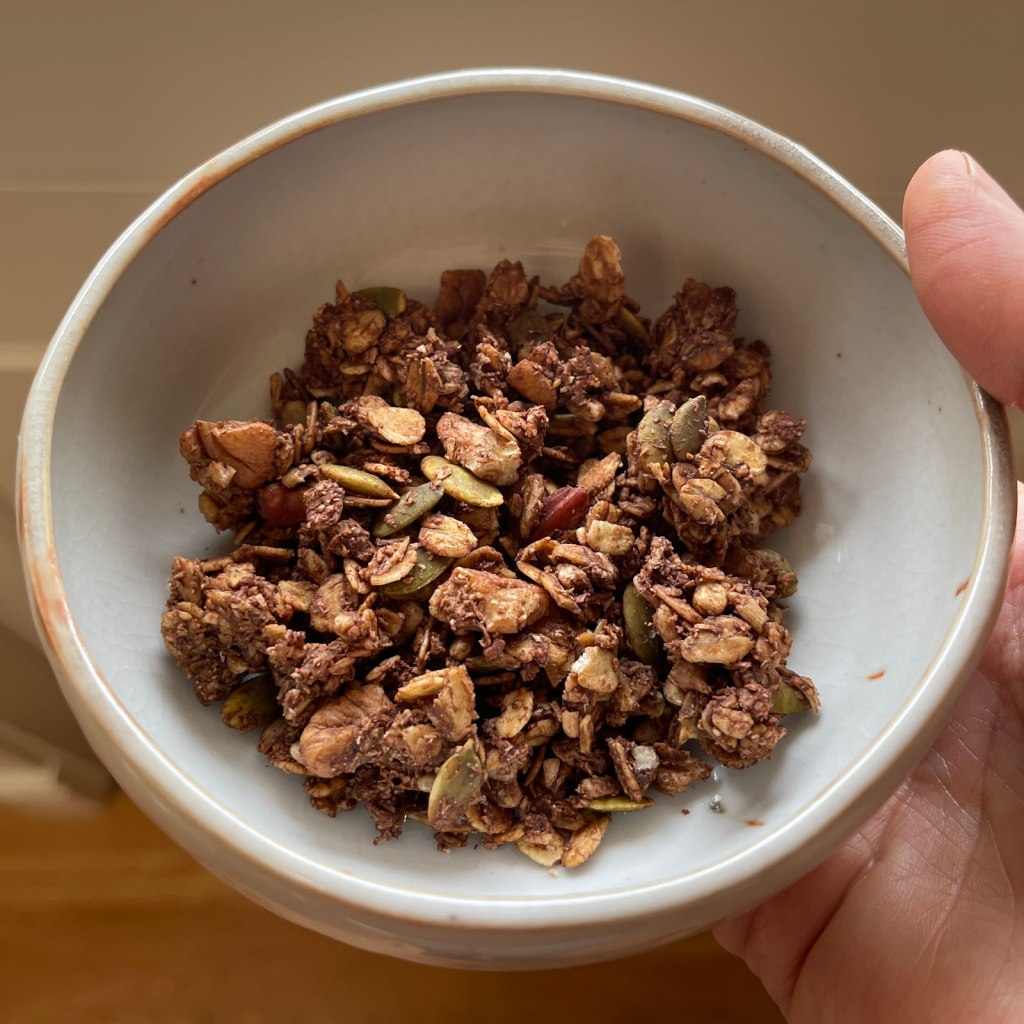 A beige ceramic bowl filled with chocolate nut granola
