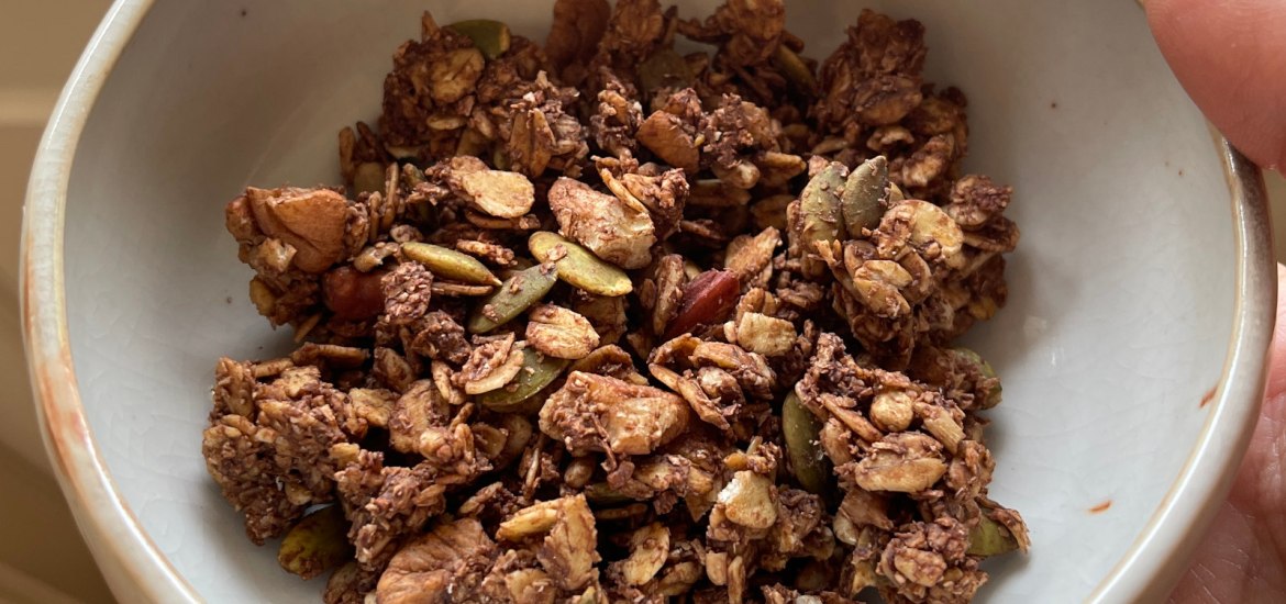 A beige ceramic bowl filled with chocolate nut granola