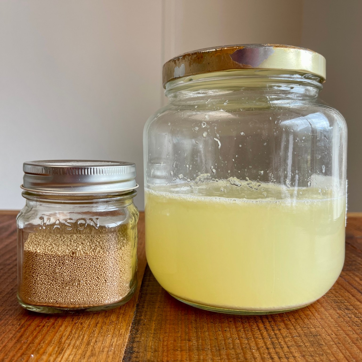 A small jar of active dry yeast sits next to a large jar of homemade lemonade.